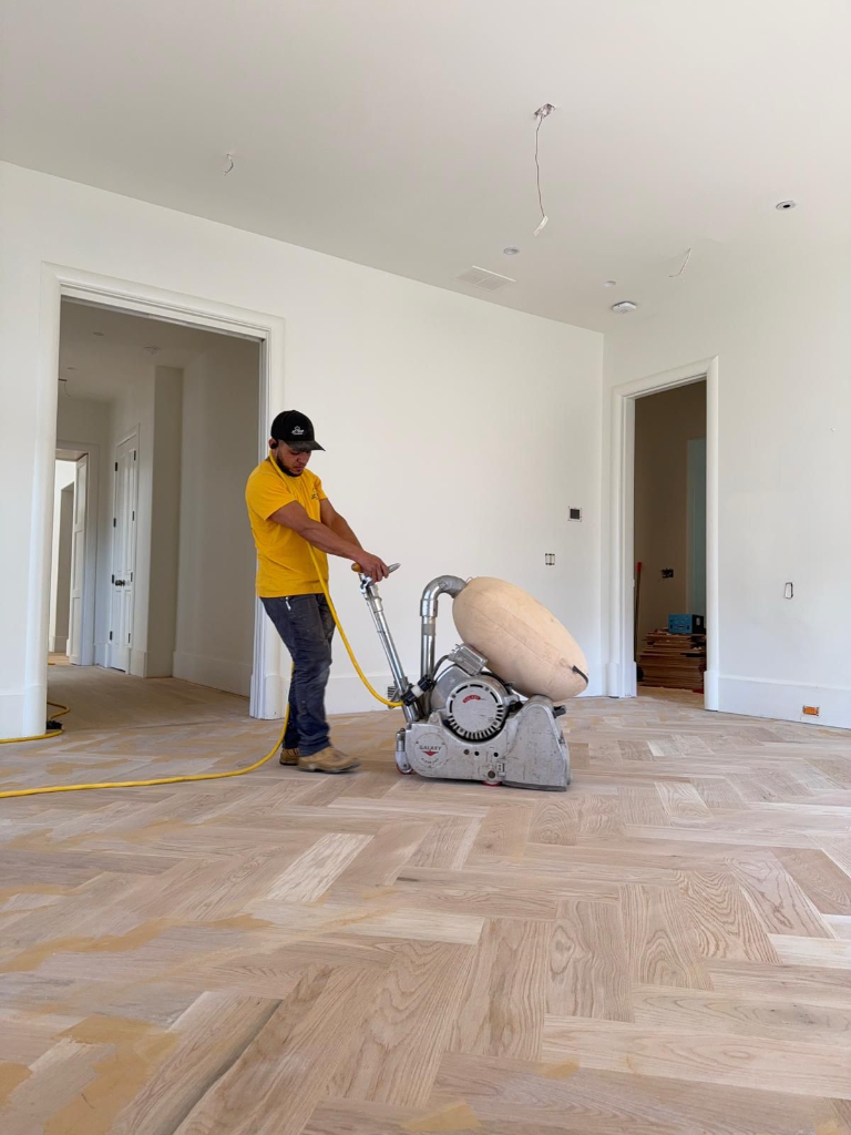 Jonas, founder of JC Top Flooring, sanding a hardwood floor